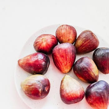 A vibrant display of fresh ripe figs on a white plate, perfect for food photography.
