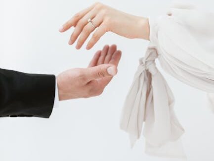 A minimalist photo featuring bride and groom exchanging rings with focus on delicate hands.