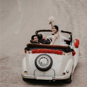 A newlywed couple celebrates their wedding in a vintage convertible adorned with roses, driving into a new future.